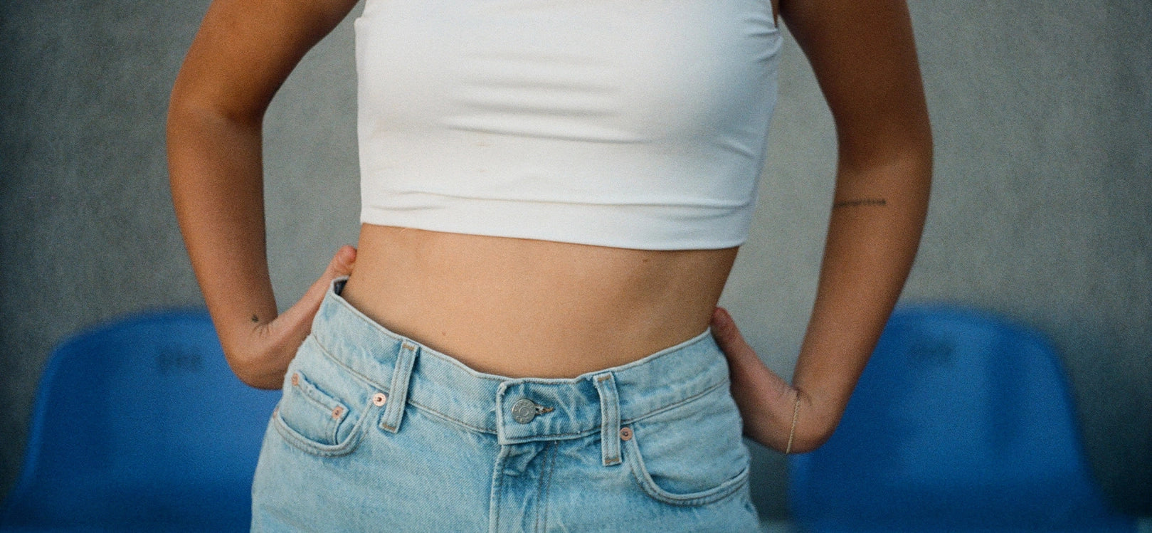 Mid-shot of woman's midriff with white crop top and blue denim shorts